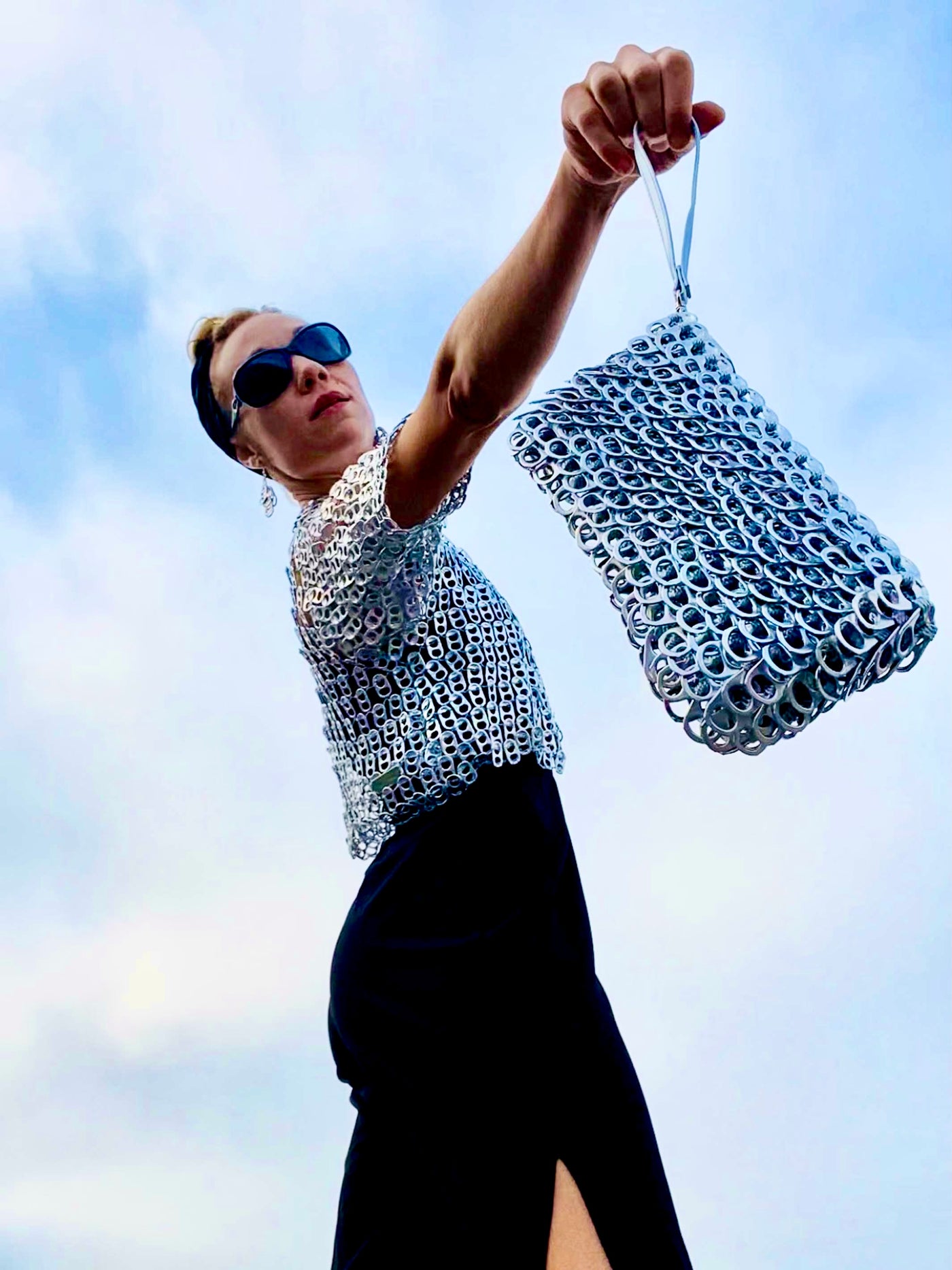 woman holding a metallic silver clutch purse made from soda tabs - escama studio